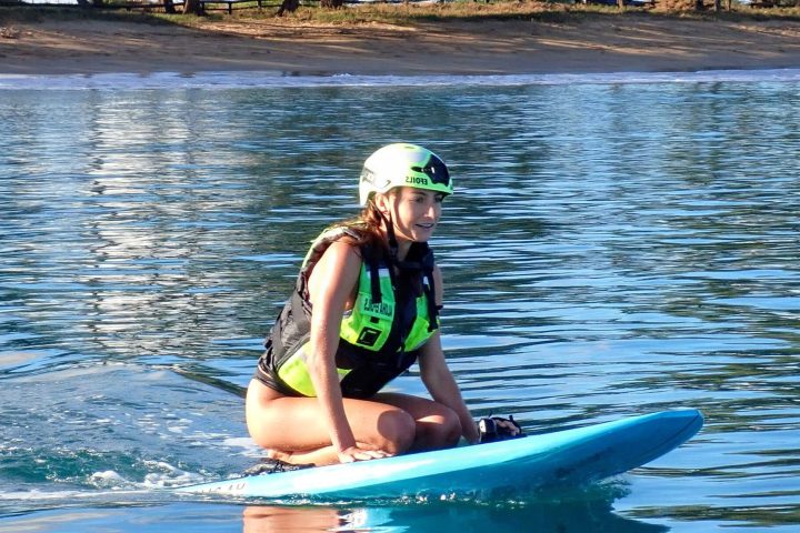 a woman riding on the back of a boat in the water