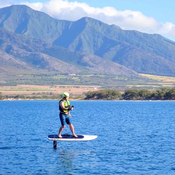 a man floating on a body of water with a mountain in the background