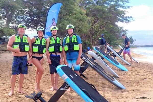 a group of people standing on top of a sandy beach holding a surfboard